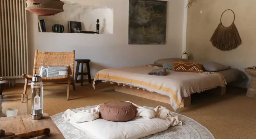 Ein gemütlicher Raum zum Meditieren einrichten: Ein Bett, ein Stuhl, Kissen und Decken laden zur Entspannung ein.