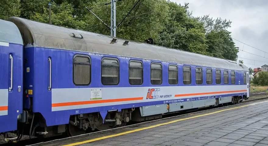 Niebiesko-szary wagon sypialny PKP Intercity stoi na torach. Wygodny przedział sypialny PKP zaprasza do podróży.