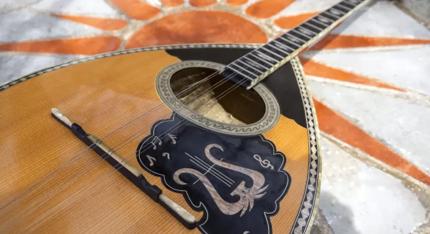 Piękny grecki instrument muzyczny, bouzouki, leży na mozaice z symbolem słońca.