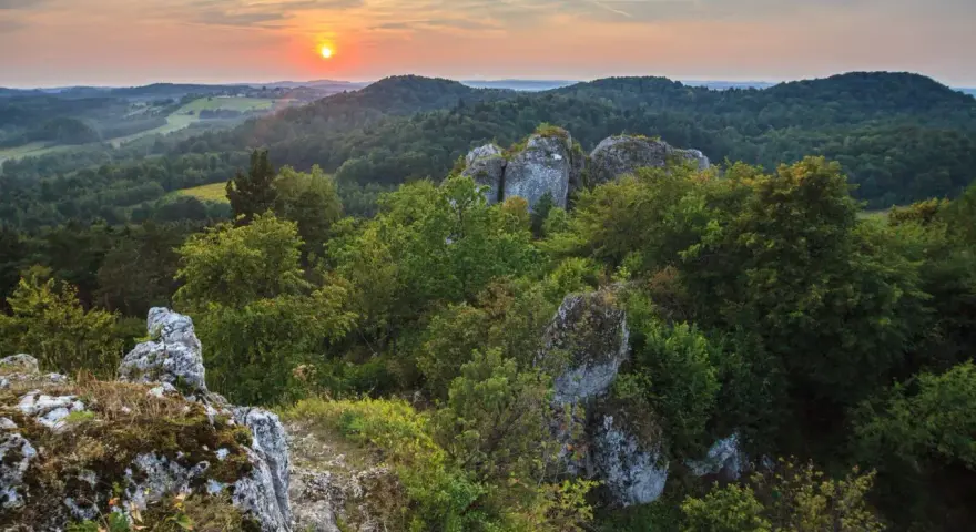 Zachód słońca nad Górami Świętokrzyskimi. Skaliste formacje i bujna zieleń tworzą malownicze krajobrazy, jedne z wielu atrakcji regionu.