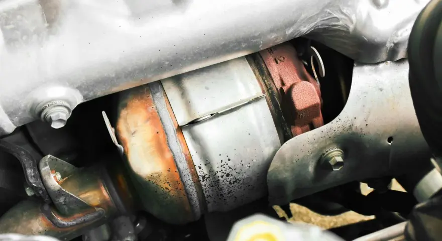 Dettaglio del sistema di scarico di un'auto, con il filtro antiparticolato (FAP) visibile. Togliere il FAP vantaggi: meno intasamenti, migliore fluidità dei gas.