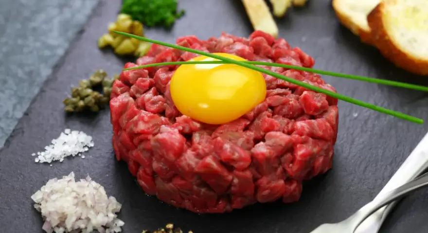 Tartare di manzo fresca e succulenta, con tuorlo d'uovo, capperi, cipolla, sale, pepe e crostini.