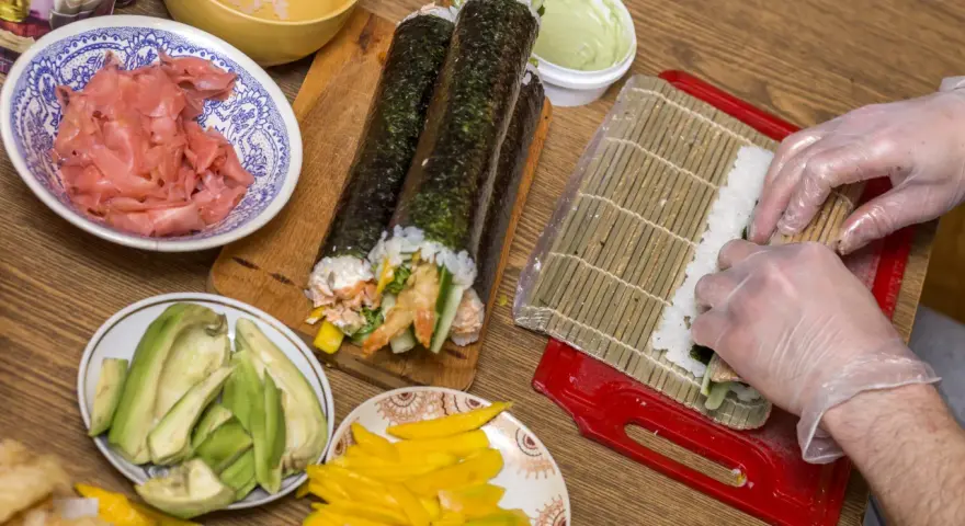 Przygotowanie sushi: ryż, awokado, mango, krewetki i marynowany imbir czekają na rolki. Zobacz nasz sushi przepis!