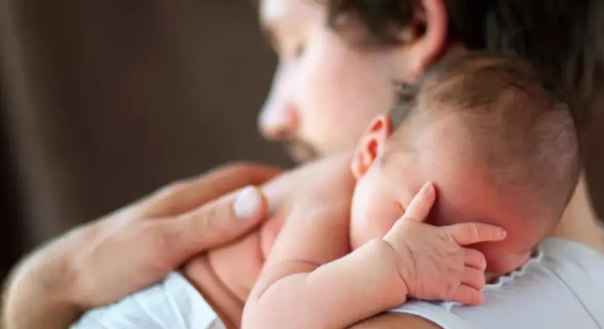 Padre abbraccia neonato. Osservare attentamente i sintomi autismo nel neonato di 3 mesi, come la mancanza di contatto visivo o risposte emotive atipiche.