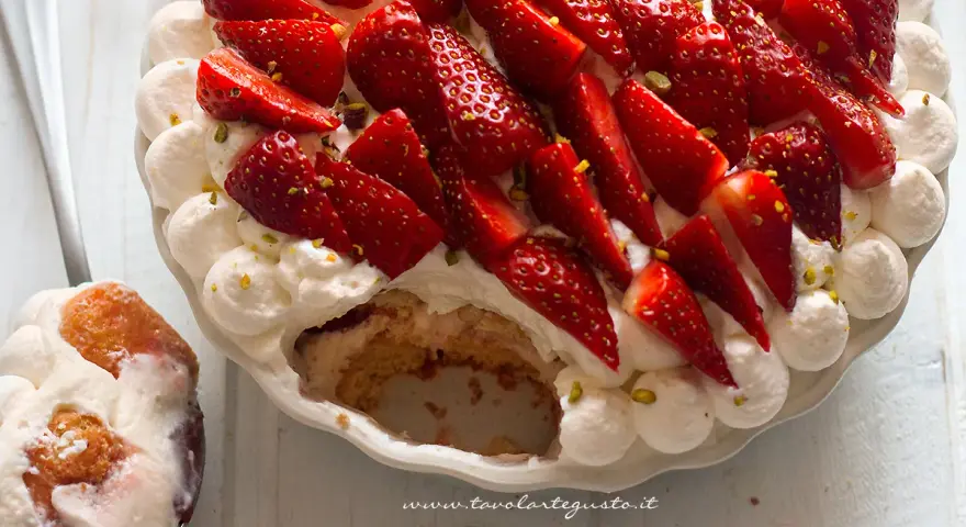 Delizioso tiramisù alle fragole, con panna montata, fragole fresche e pistacchi tritati. Una fetta è già stata servita.