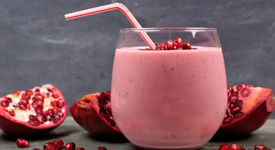 Orzeźwiający drink z granatem, udekorowany nasionami i kawałkami owocu. Idealny na letnie popołudnie.