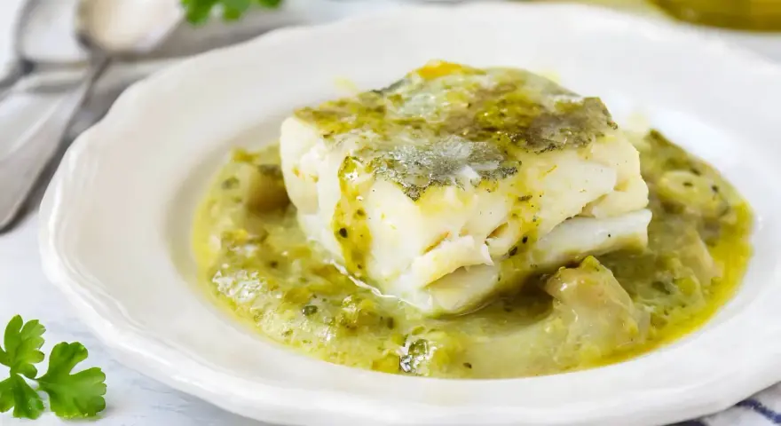Un trozo de merluza a la vasca, jugoso y tierno, bañado en una salsa verde cremosa con trozos de pimiento.
