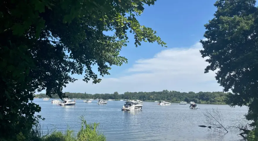 Boote auf dem Glindower See unter blauem Himmel, umgeben von grünen Bäumen. Ein sonniger Tag am Wasser.