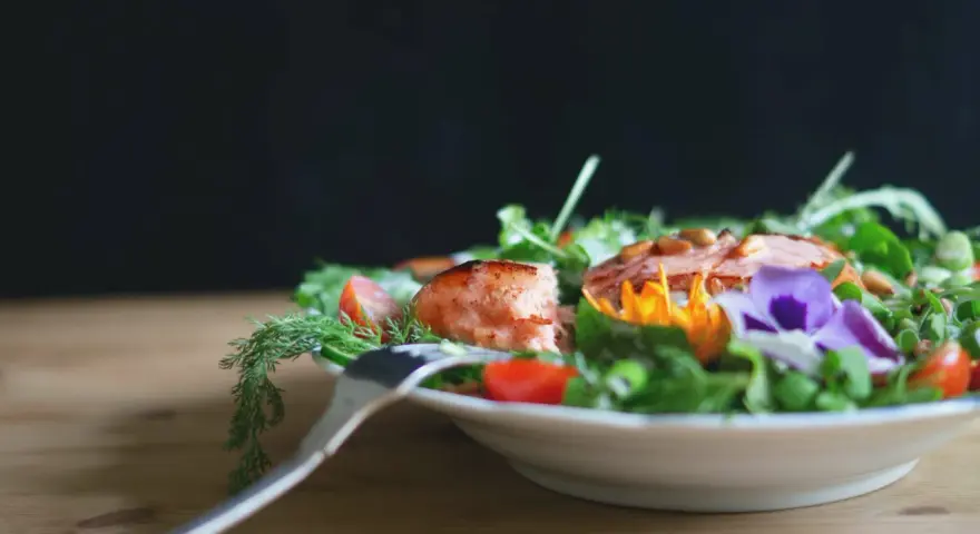 En vacker sallad med lax, tomater och ätbara blommor. Perfekt för att deffa mat och njuta av en hälsosam måltid.