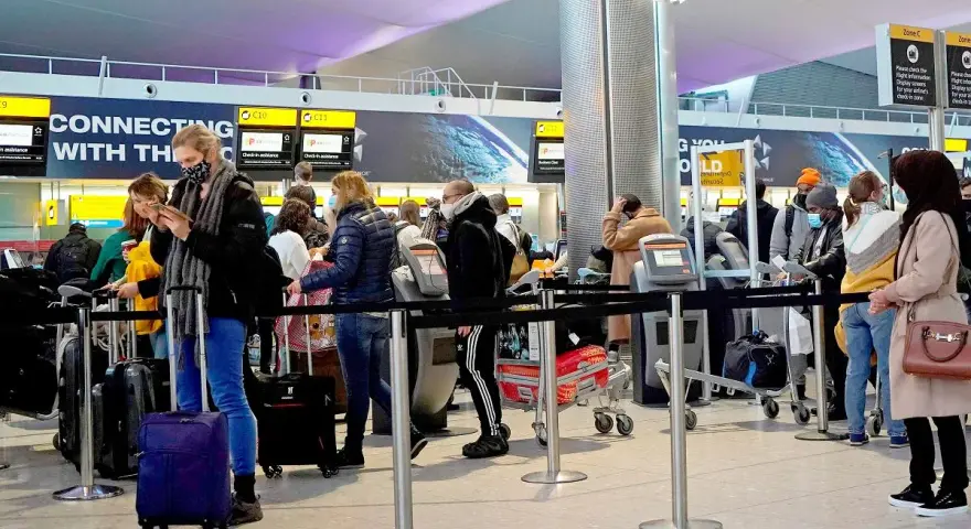 Kolejka do odprawy na lotnisku, przypominająca terenową delegaturę paszportową w Bielsku-Białej. Ludzie z bagażami czekają na swoją kolej.