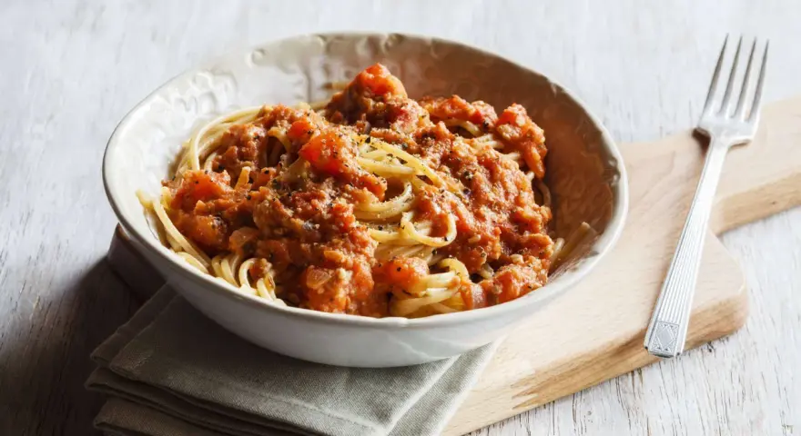 Eine Schüssel Spaghetti mit einer herzhaften, tomatigen Bolognese-Sauce, perfekt für eine schnelle Mahlzeit.