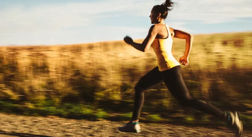 Kvinna springer i full fart, ett intensivt hiit pass utomhus.