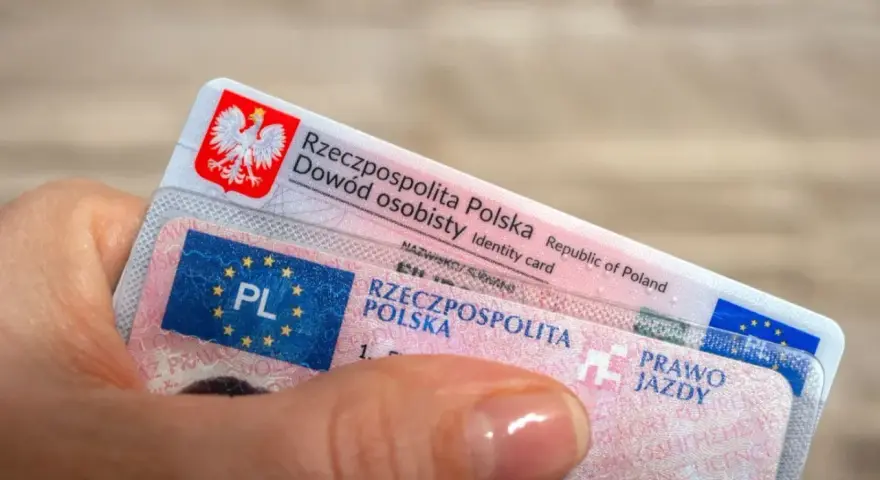 Dłoń trzyma polski dowód osobisty i prawo jazdy. To dokumenty, które pozwalają na swobodne podróżowanie, a prawo jazdy bezterminowe daje spokój na lata.