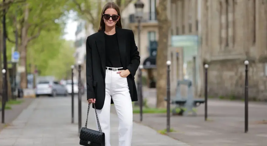 Donna con blazer nero, jeans bianchi e borsa Chanel, un look che aiuta a sembrare più alto.