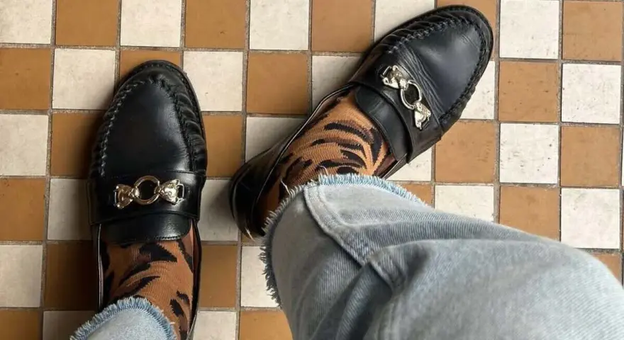 Elegantes mocasines negros con detalle de tigre en los calcetines, un ejemplo de los diversos tipos de mocasines.