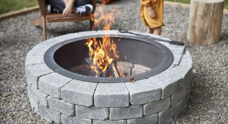 A stone fire pit with a roaring fire, perfect for a backyard gathering. This image shows how to build a fire pit for cozy evenings.