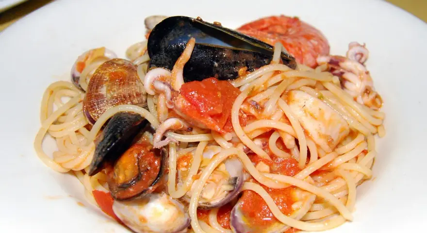 Spaghetti allo scoglio con cozze, vongole, calamari e pomodoro. Un piatto di mare ricco e saporito.