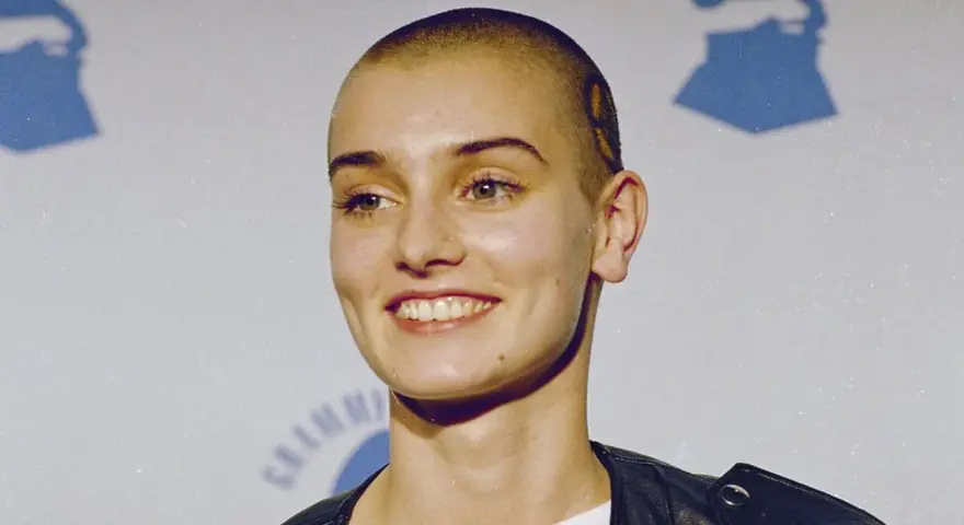 Uśmiechnięta Sinéad O'Connor z ogoloną głową, w czarnej ramonesce. Jej spojrzenie mówi, że nic nie porównuje się do Ciebie.