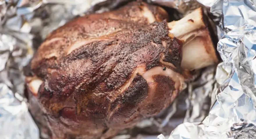 Stinco di maiale succulento, cotto alla perfezione e avvolto in carta stagnola, pronto per essere gustato.