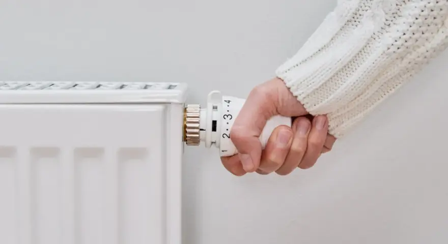 Mano girando la perilla del radiador para saber como encender la calefacción desde la caldera.