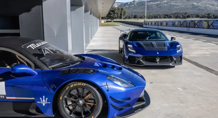 Dwa niebieskie Maserati na torze wyścigowym. Jedno z nich, z bliska, ma na oponach napis Pirelli P Zero.