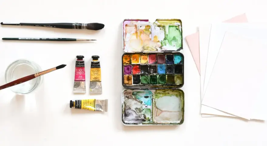 Matériel d'artiste : palette de peinture, tubes de couleur, pinceaux et papier pour le support aquarelle.