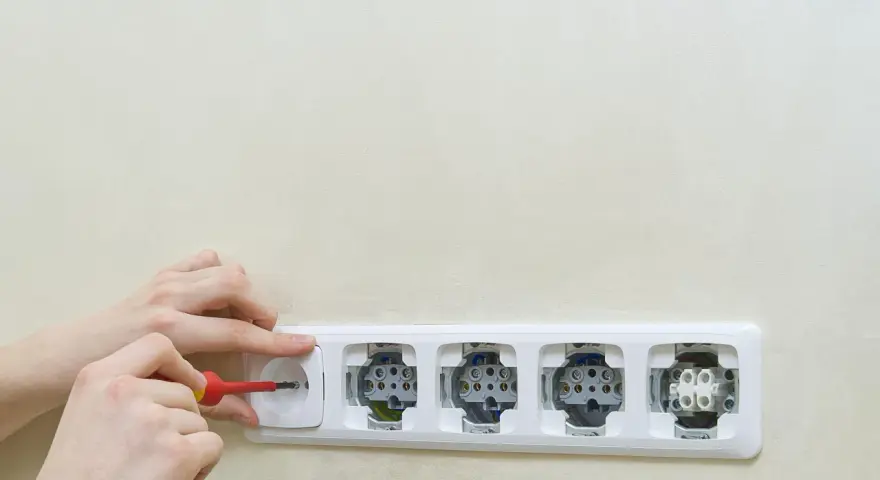 Ręce montują gniazdka elektryczne. Dowiedz się, jak podłączyć oświetlenie z gniazdka, wykonując te czynności.