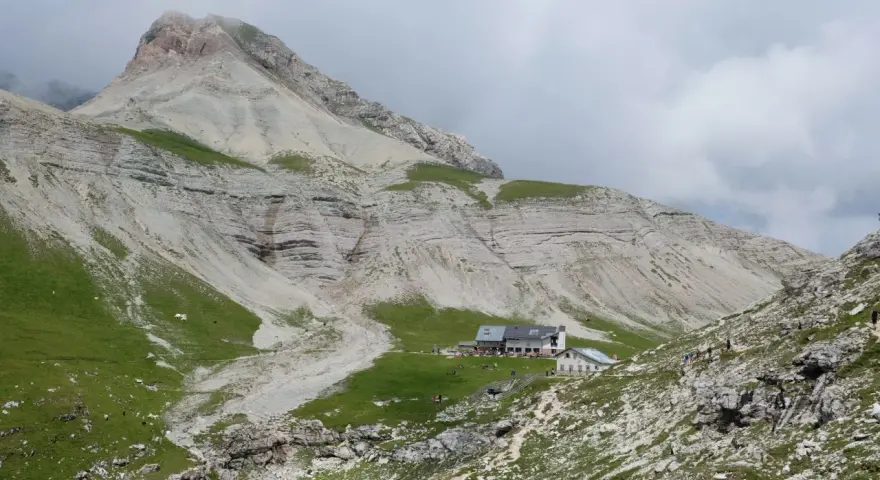 Rifugio alpino con escursionisti e gregge in un paesaggio montano mozzafiato, vicino a Passo Val Gardena.