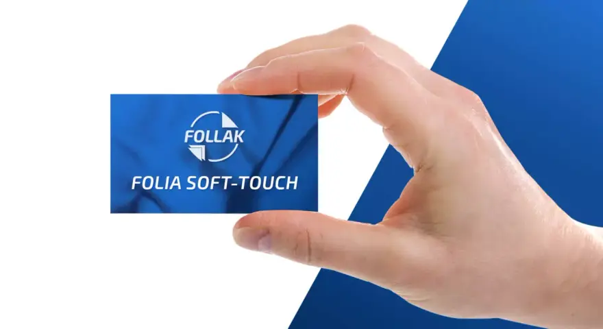 Dłoń trzyma kartę z napisem "Folia Soft-Touch" od FOLLAK, prezentując efekt laminacji.