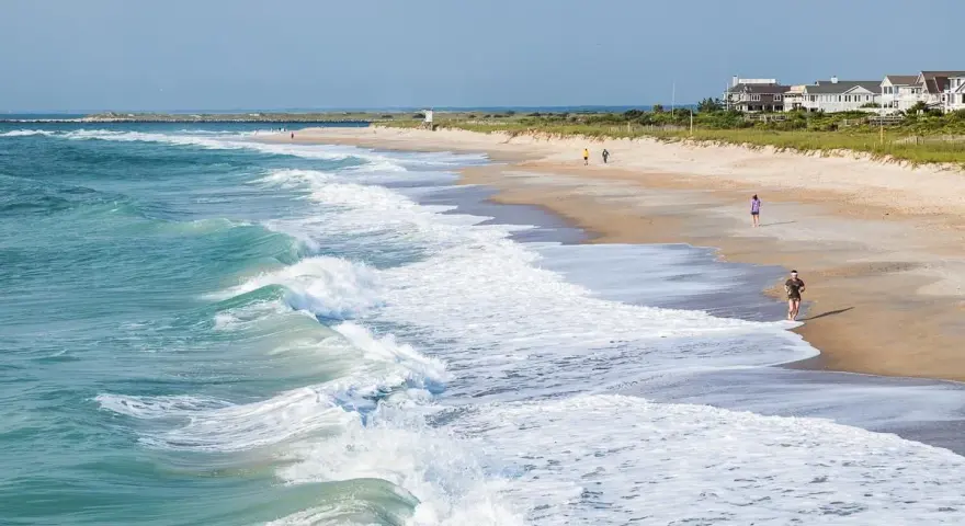 Waves crash on the shore at Wrightsville Beach, where people enjoy a run and a stroll, showcasing some of the relaxing things to do.