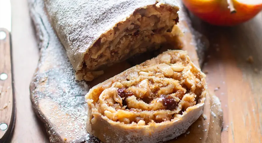 Un delizioso strudel di mele, cosparso di zucchero a velo, con un ripieno ricco di mele, uvetta e pinoli.