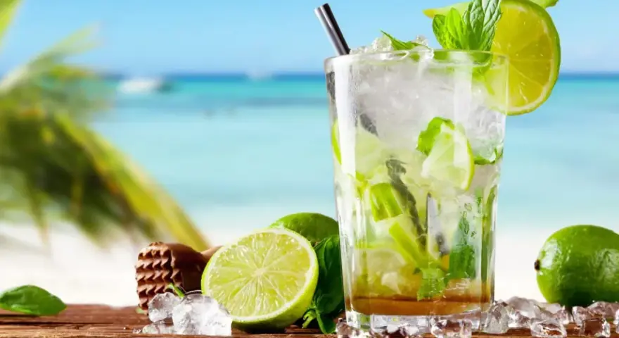 Orzeźwiający koktajl mojito z limonką i miętą na tle plaży. Idealny przepis na lato.