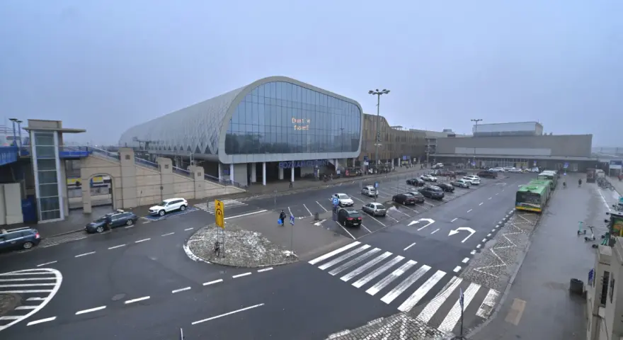 Dworzec Poznań Główny, z nowoczesną architekturą i parkingiem pełnym samochodów, gotowy na podróżnych do Nowego Tomyśla.
