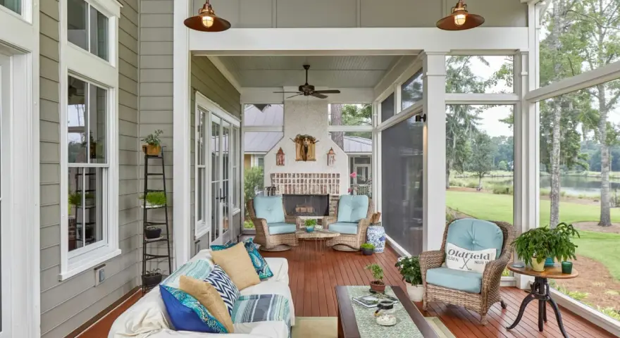 A cozy screened-in patio with a fireplace, wicker chairs, and a sofa, perfect for enjoying the view of the lake.