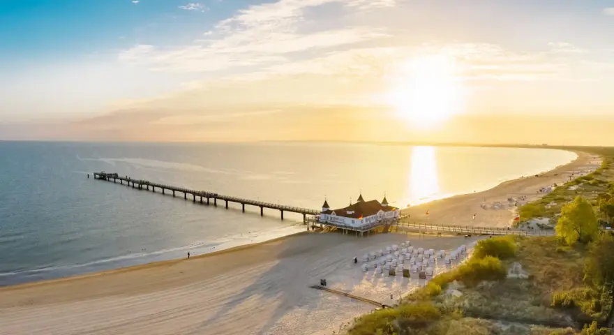 Sonnenuntergang am Ostsee Strand mit langer Seebrücke und Strandkörben.