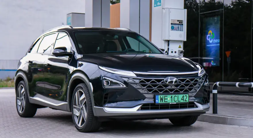 Czarny Hyundai Nexo, jeden z samochodów na wodór, tankuje na stacji.