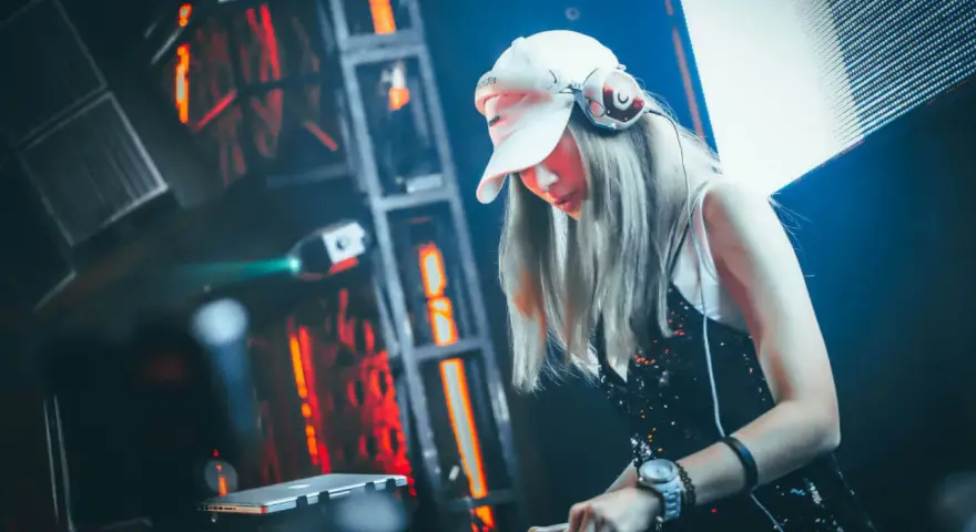 DJane legt auf, die Menge tanzt zu fetter electro dance music. Rote Lichter blitzen, die Musik pulsiert.