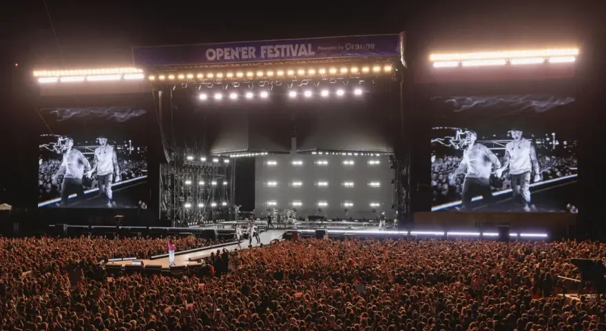 Ogromny tłum na Opener Festival, **ile ludzi**! Na scenie artyści, a na telebimach ich wizerunki.