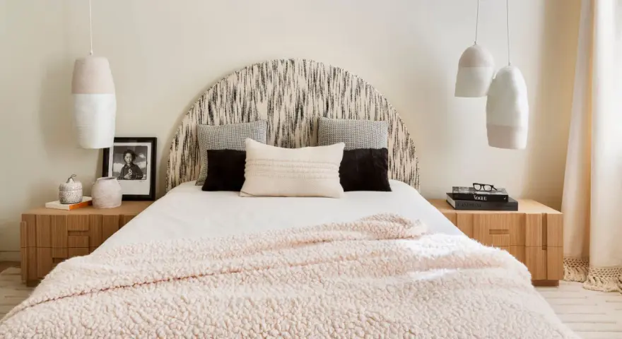 Camera da letto con testiera a semicerchio, cuscini decorativi e coperta rosa. Lampade a sospensione e comodini in legno completano l'arredamento, creando camere aesthetic.