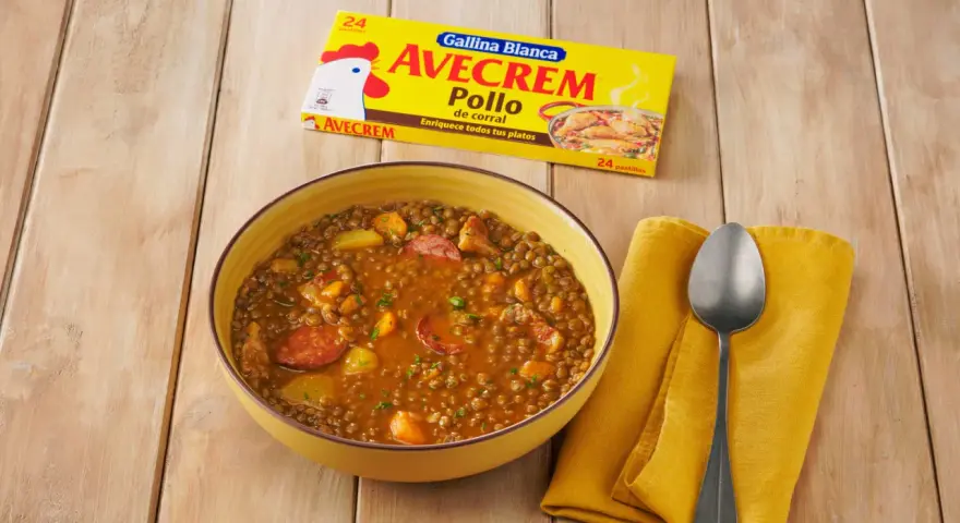 Un tazón de lentejas estofadas con chorizo y patatas, junto a un paquete de Avecrem Pollo.