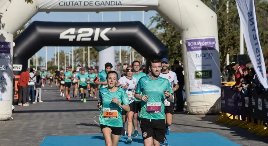 Corredores cruzan la meta de la distancia media maratón en Gandía.