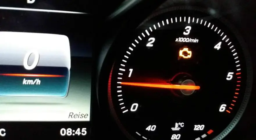 Gelbe motorkontrollleuchte leuchtet auf dem Armaturenbrett. Der Tachometer zeigt 0 km/h.