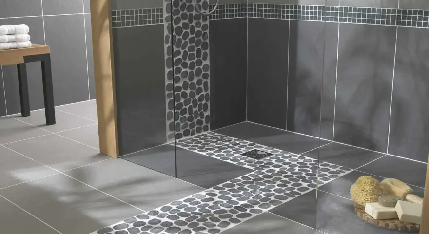 Carrelage moderne avec un chemin de galets sur le receveur de douche, créant une ambiance zen.