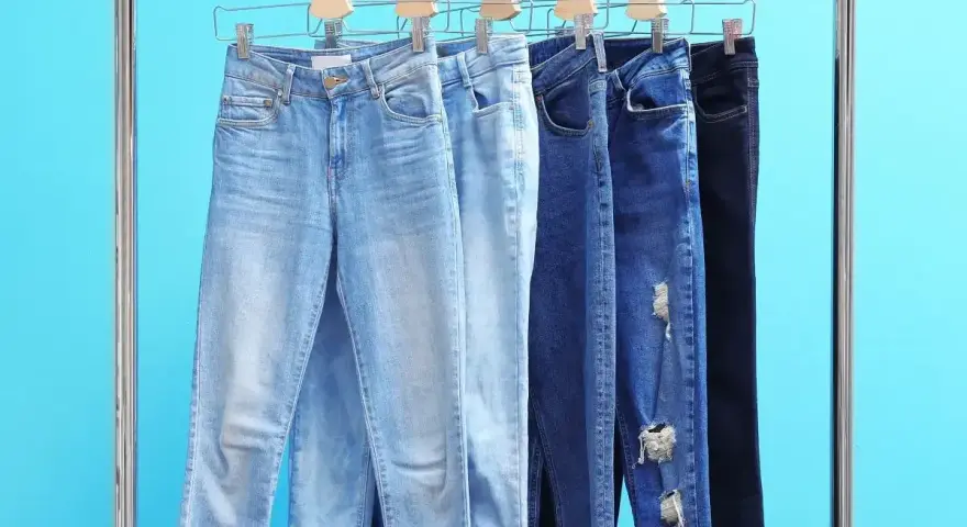 Różne modele jeansów na wieszakach. Czy rozmiar 27 spodnie damskie to Twój idealny rozmiar?