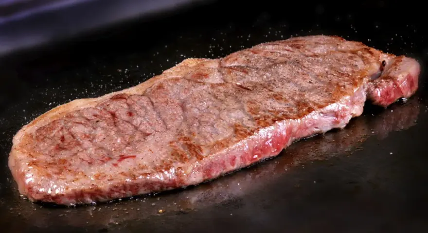Filete de ternera jugoso cocinándose en una plancha. Perfecto para tus recetas con filetes de ternera.