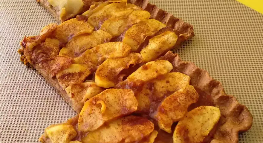 Dos porciones de tarta de manzana casera, con trozos de manzana dorados y espolvoreados con canela, sobre una base de masa crujiente.