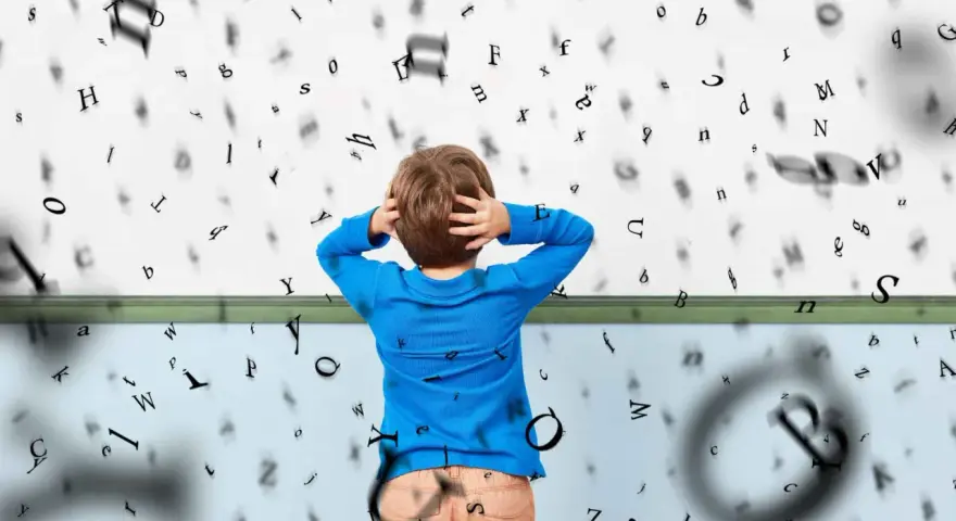 Chłopiec z rękami na głowie, otoczony wirującymi literami, symbolizuje trudności z czytaniem, czyli dysleksję u dzieci.