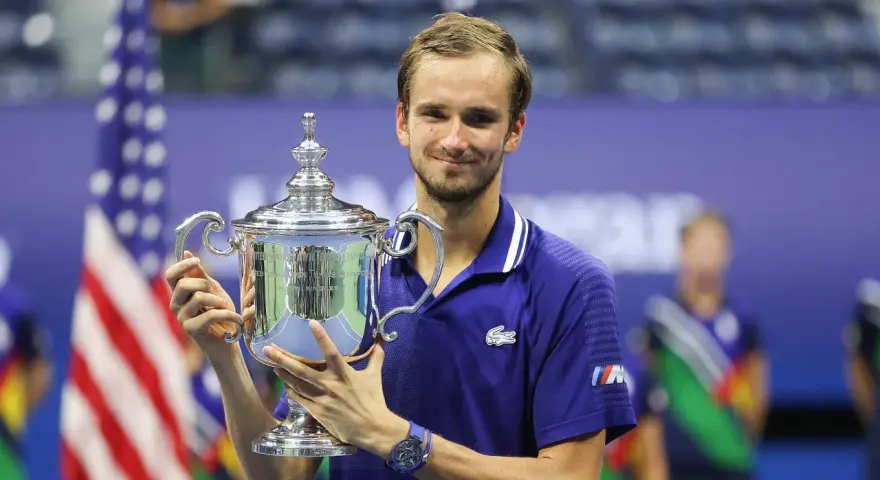Daniil Medvedev, sonriendo, sostiene el trofeo del US Open, un logro que lo consolida entre los grandes de los medvedev grand slams.
