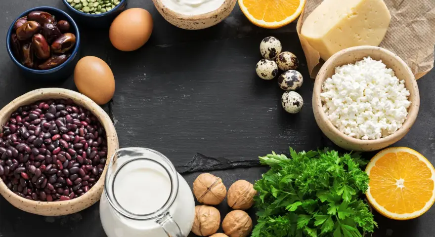 Vielfalt an Lebensmitteln mit Calcium: Milch, Käse, Quark, Eier, Bohnen, Datteln, Nüsse, Orangen und Petersilie.