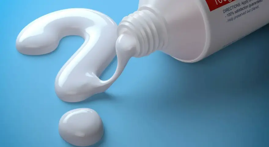 Biała pasta do szczoteczki sonicznej tworzy znak zapytania na niebieskim tle.